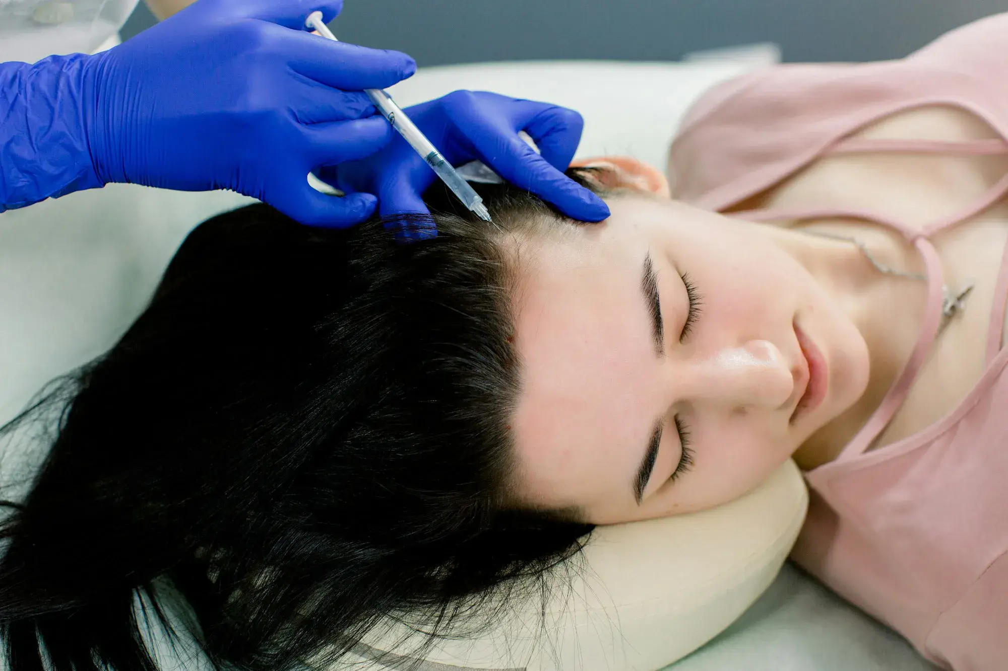Hair mesotherapy or hair transplant: a beautician doctor makes injections in the head of a woman for