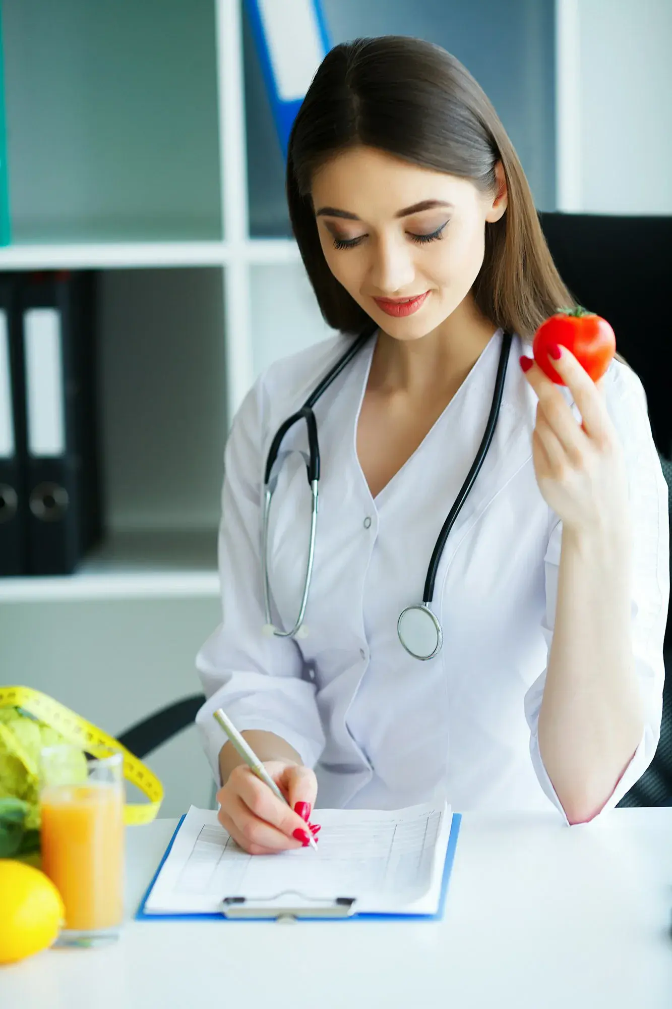 The doctor signs out a diet plan. The Dietitian Holds in the Handfuls of Fresh Tomato.